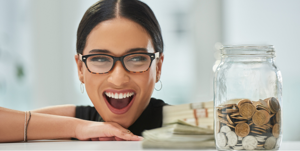 Close up of woman looking at a jar of coins on a counter.